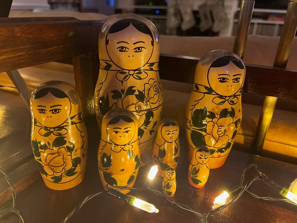 Set of 7 Russian Matroyshka dolls, also known as nesting dolls.  The dolls are shown here not nesting, but displayed amongst Christmas lights.
