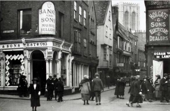 An early twentieth century scene from York, showing part of Stonegate and featuring the corner shop at that time occuped by Banks and Sons Music Sellers. York Minster is visible in the background